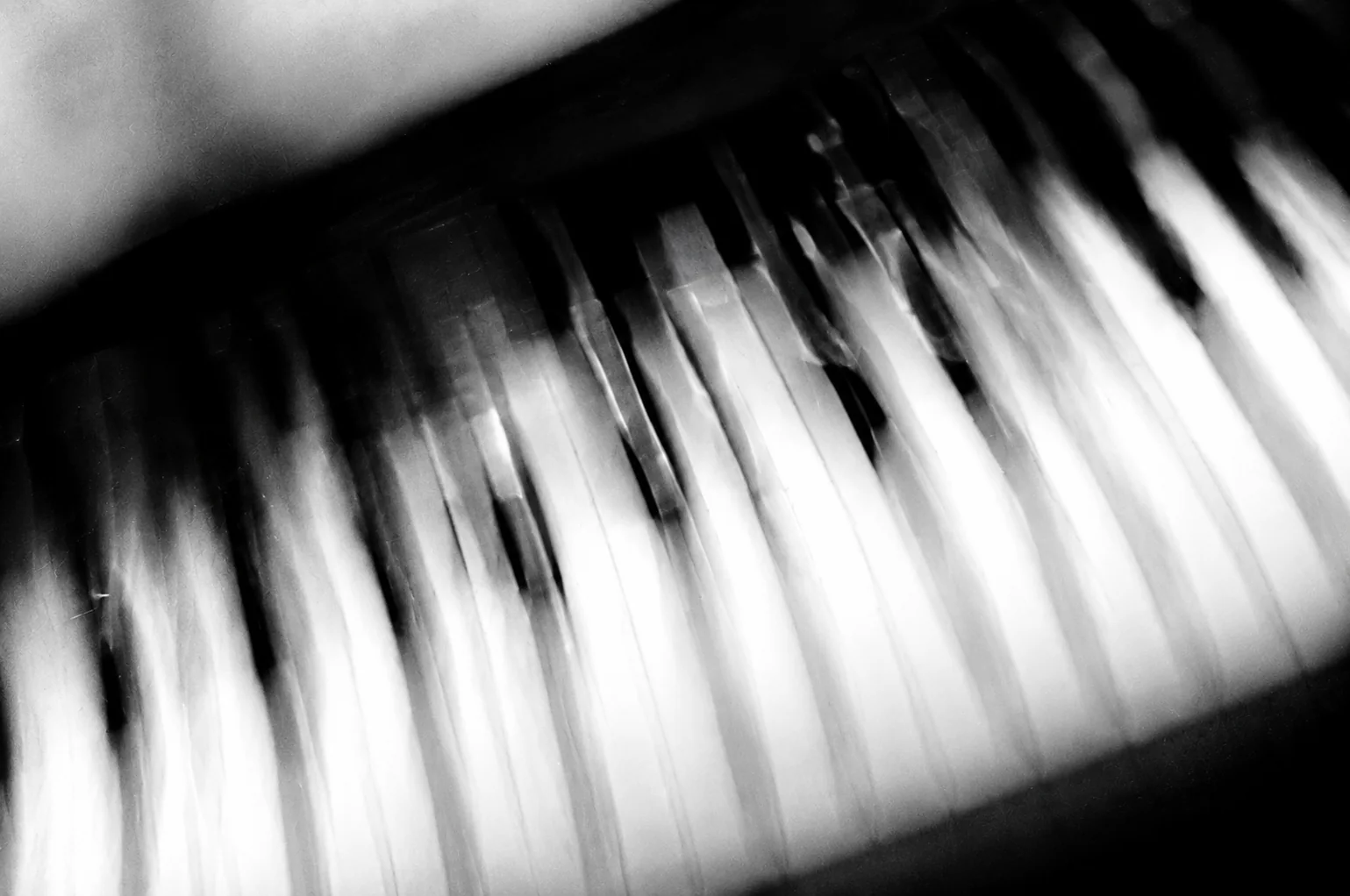 Black-and-white piano keys stretching into soft vertical streaks of motion.